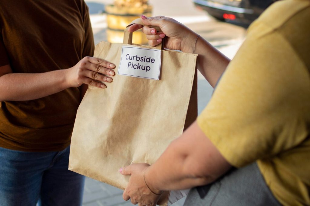 Customer receiving a curbside order in branded kraft bags