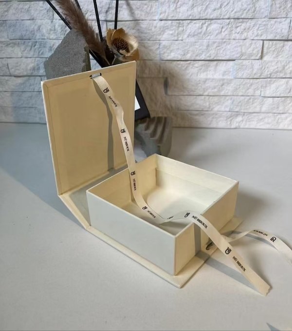 Elegant white gift box with ribbon, open lid exposing interior compartments