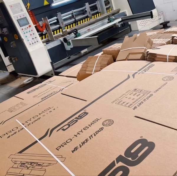 Stacks of branded cardboard boxes near manufacturing equipment