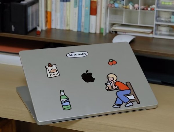 Laptop with quirky stickers including a seated figure and text "so it goes"