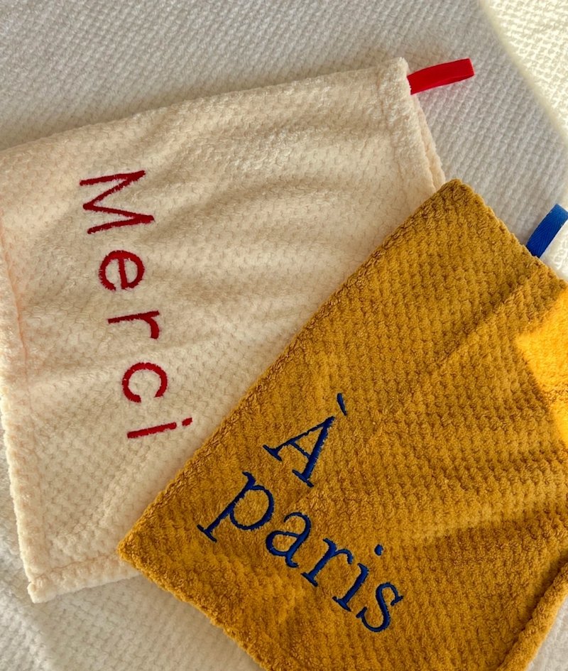 Soft embroidered towels with "Merci" and "À Paris" text in red and blue