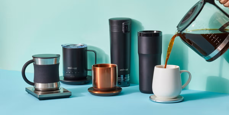 Various smart mugs and tumblers with coffee being poured into a white mug