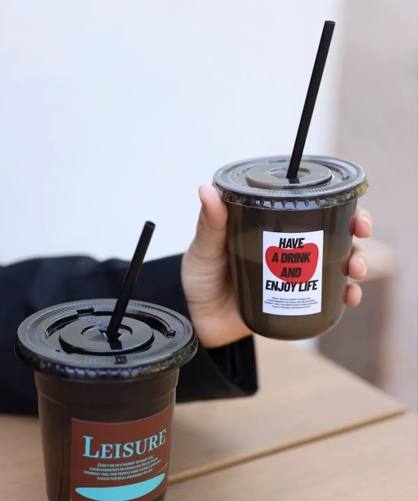 Two takeaway drinks with black lids and motivational stickers