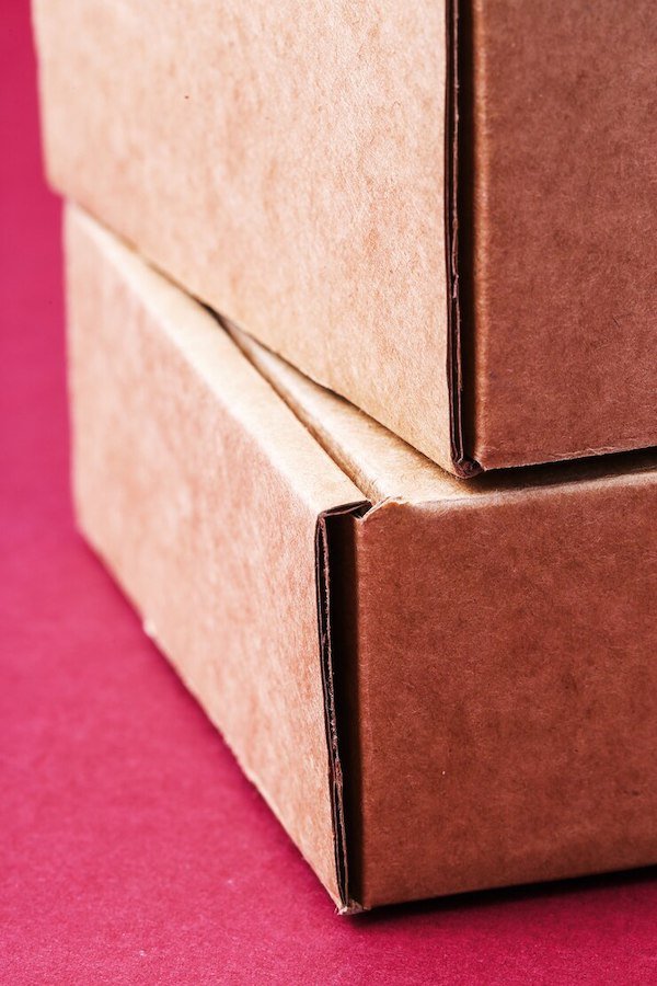 Close-up of stacked brown cardboard boxes against a red background