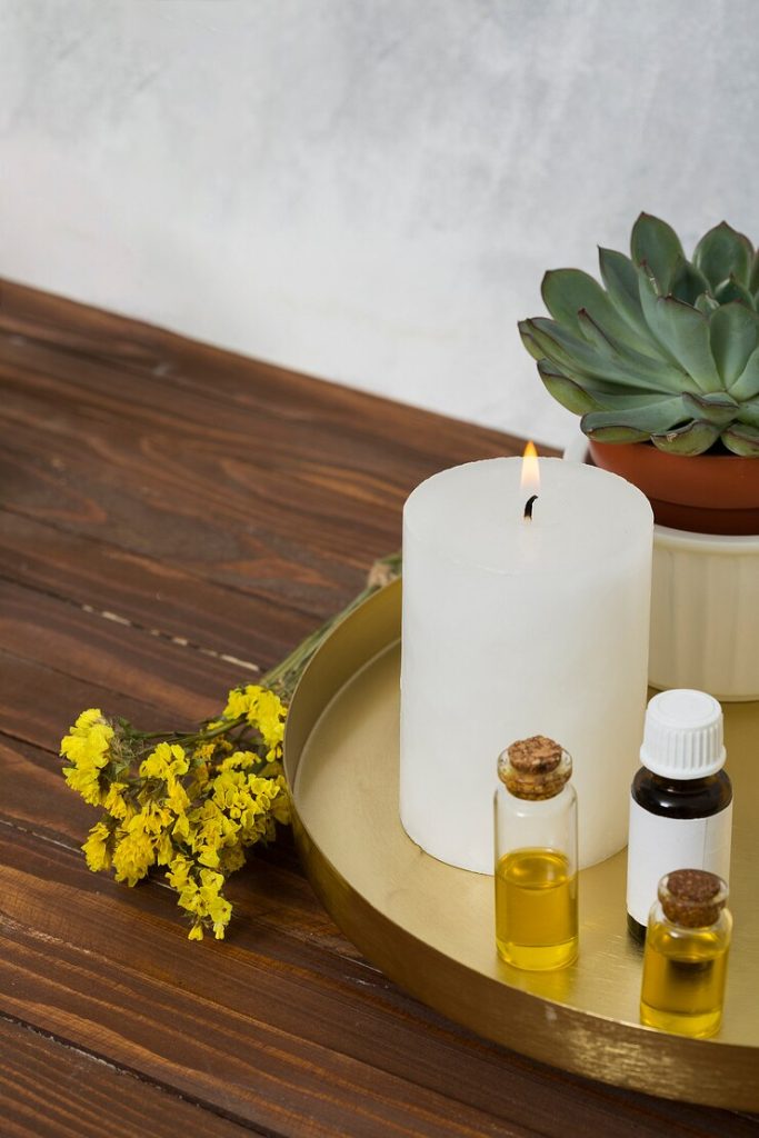 lit candle with dried flowers and an essential oil bottle
