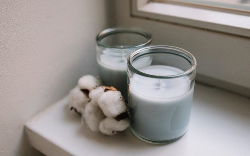 two white candle jars with a cotton wick