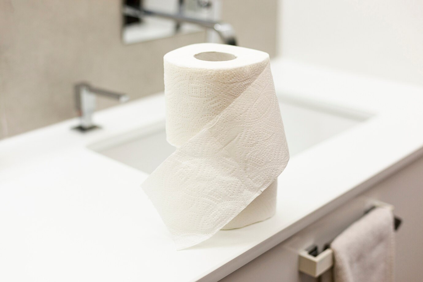 Toilet paper roll placed on a white bathroom sink countertop