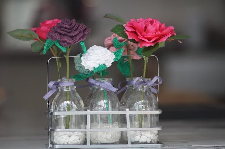 Colorful artificial flowers in glass bottles
