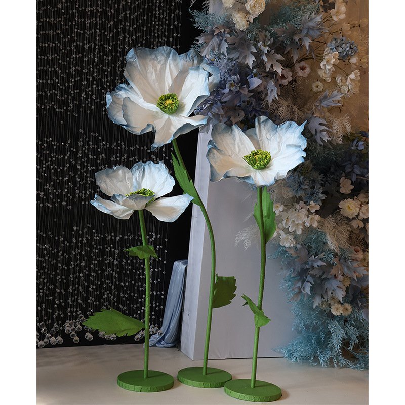 Large white paper flowers with green stems in a decorative display