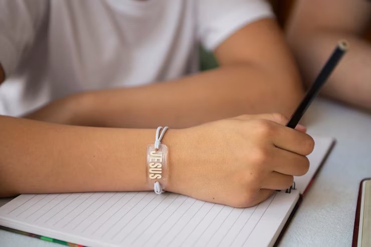 hand with "JESUS" bracelet while writing