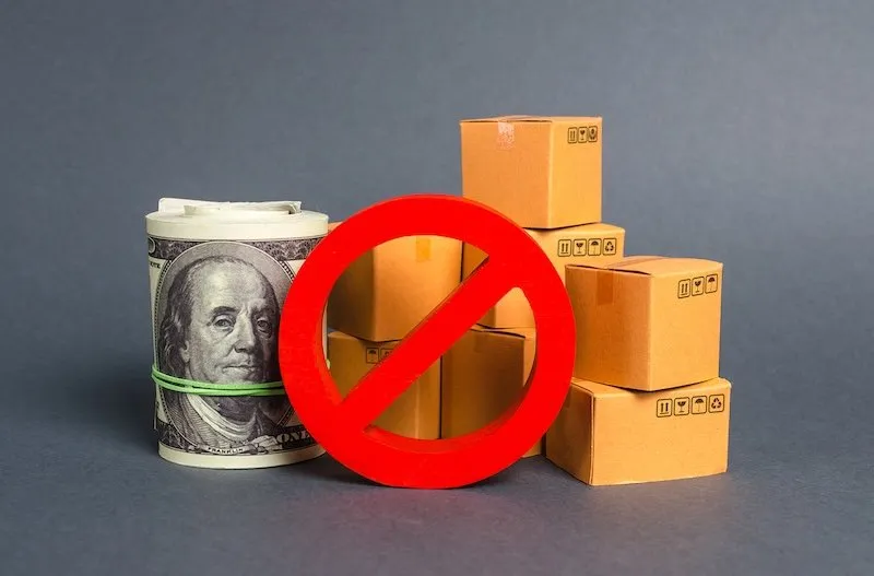 Prohibition sign over money and boxes representing trade restrictions