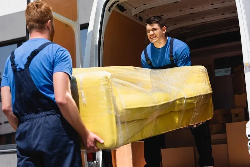 Two men carrying a sofa during a furniture delivery